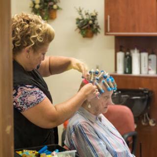 A hair stylist applies color foils to a client's hair in a cozy salon setting.