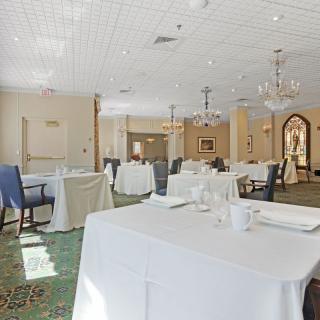An elegant dining room with white tablecloths and chandeliers.