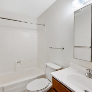 A clean and minimalist bathroom featuring a bathtub, toilet, and sink.