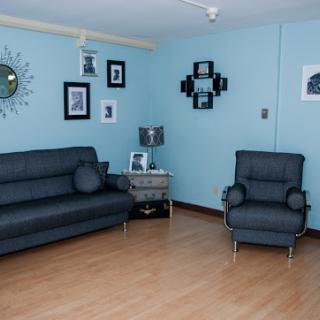 A cozy living room featuring a blue color scheme, modern furniture, and decorative wall art.