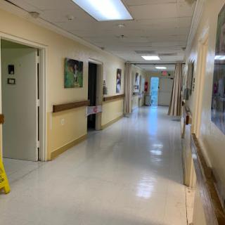 A clean and bright hospital hallway with doors and artwork along the walls.