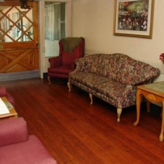 A cozy living room with a sofa and armchairs on a hardwood floor, decorated with a painting and a table.