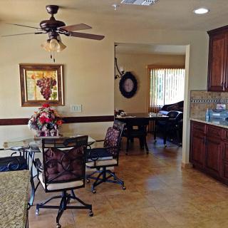 A cozy dining area connected to a kitchen, featuring a ceiling fan and elegant decor.