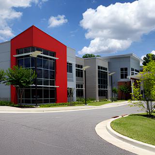A modern office building with a striking red accent wall under a partly cloudy sky.