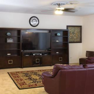A spacious living room with a large entertainment center and cozy seating arrangement.