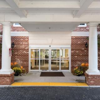 Entrance to a brick building with glass doors and surrounding columns.