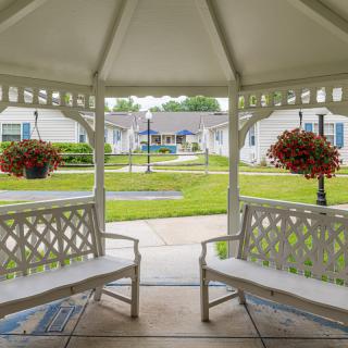 View from a gazebo overlooking a garden with benches and flower arrangements.
