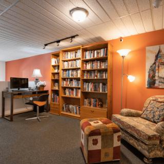 A cozy living room with a bookshelf, desk, and comfortable seating area.