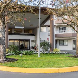 A well-maintained building entrance surrounded by trees and landscaping.