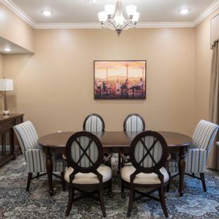 A well-lit dining room featuring a wooden table with six chairs, a chandelier, and artwork on the wall.