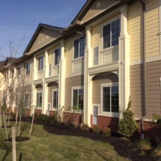 A row of modern townhouses with landscaped yards in a suburban neighborhood.