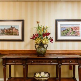 A beautifully arranged interior featuring a wooden console table adorned with a floral centerpiece and framed artwork on the walls.