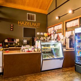 A cozy cafe interior featuring a counter with a display case and refrigerator.