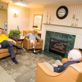 A group of elderly men having a conversation in a cozy living room.