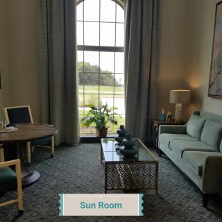 A cozy sunroom with a sofa, table, and large window providing natural light.