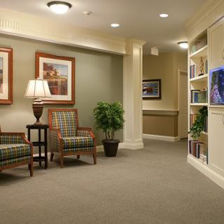 A cozy lobby area featuring comfortable chairs, a lamp, a potted plant, and decorative artwork.