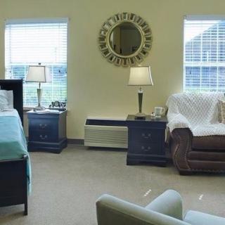 A cozy bedroom interior with natural lighting, featuring comfortable furniture and decorative elements.