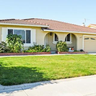 A suburban single-story house with a well-maintained lawn and garden.