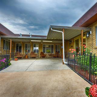 A courtyard outside a building with a concrete patio and vibrant flowers under a cloudy sky.