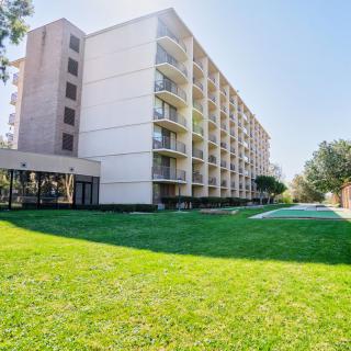 A residential apartment building with balconies and a well-kept lawn in front.