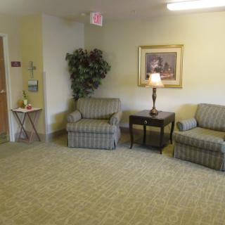 A cozy lobby area with two upholstered chairs, a lamp on a side table, and framed artwork on the wall.