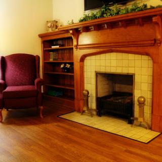 A cozy living room featuring a wooden fireplace and a comfortable purple armchair.