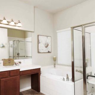 A modern bathroom with a bathtub, glass shower, and vanity area.