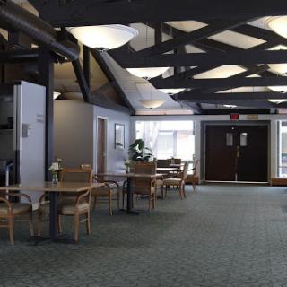 A spacious and inviting lobby area with tables, chairs, and natural light.
