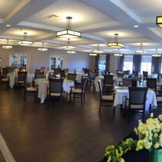 A spacious dining room with neatly arranged tables and chairs, featuring elegant lighting and decor.