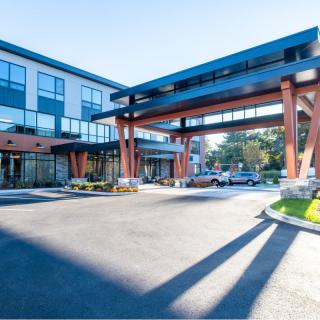 A modern hotel entrance with a covered driveway under a clear blue sky.