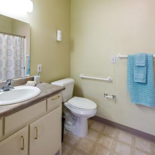 A clean and simple bathroom with a sink, toilet, and blue towels.