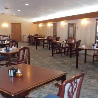 An empty dining room with wooden tables and chairs arranged neatly.