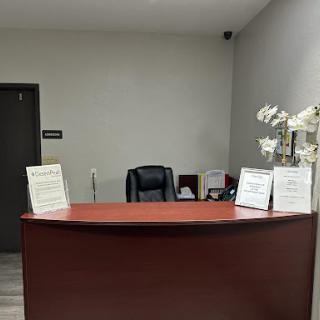A quiet reception area with a wooden desk, comfortable chair, and decorative flowers.