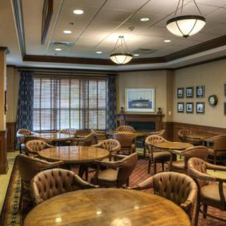 A cozy lounge area with wooden tables and chairs arranged for a meeting or gathering.