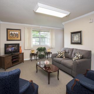 A cozy living room with a sofa, armchairs, and a television.