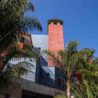 A modern urban building with colorful exterior and palm trees against a clear blue sky.