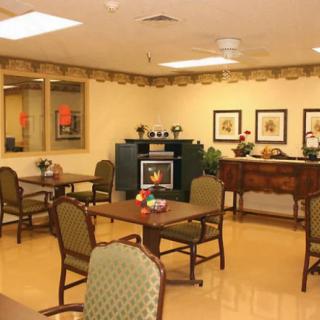 A cozy dining area with neatly arranged tables and chairs, complemented by warm decor and framed artwork on the walls.