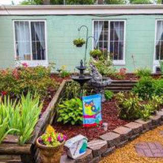 A charming garden with a central fountain, surrounded by greenery and decorative elements in front of a house.