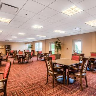 An empty dining area with tables and chairs arranged neatly on a carpeted floor.