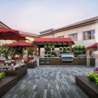 A beautifully designed outdoor patio with seating, a barbecue area, and vibrant red umbrellas.