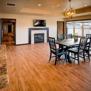 A modern dining room with hardwood floors, a chandelier, and a fireplace.