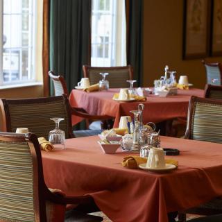 An elegantly set dining room with tables prepared for guests.