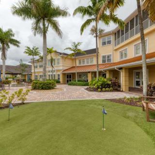 A landscaped outdoor area with palm trees and a patio in front of a multi-story building.