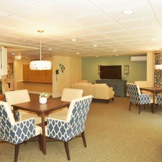 A spacious living area with dining tables, comfortable seating, and a television.