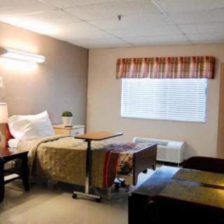 A well-organized hospital room with a single bed, side table, and a window.