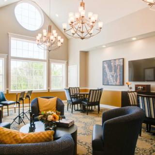 A stylish living room with elegant chandeliers, comfortable seating, and large windows.