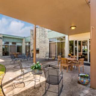 A modern patio with seating under a covered area, featuring tables and chairs in an open-air setting.