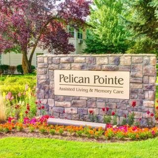 Sign for Pelican Pointe Assisted Living & Nursing Care surrounded by landscaped flowers.