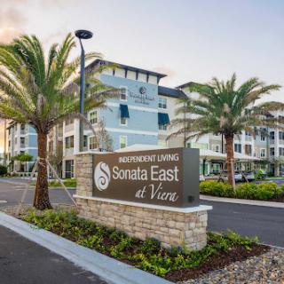 Entrance to Sonata East at Vine, featuring modern architecture and lush landscaping.