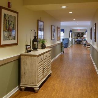A warmly lit hallway with paintings on the walls and a decorative sideboard.
